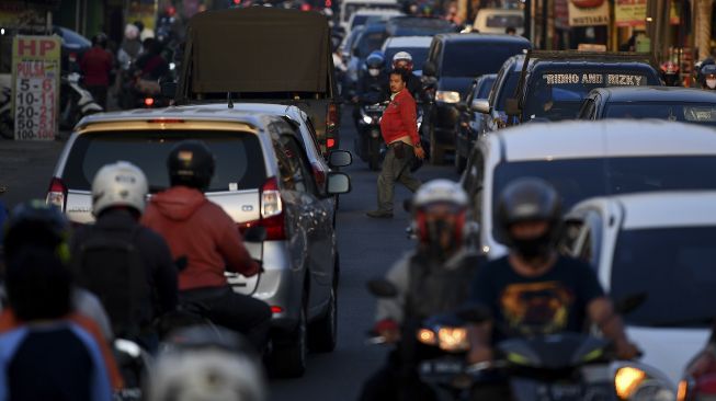 Seorang warga menyeberang jalan di tengah keramaian lalu lintas di Jalan Raya Sawangan, Depok, Jawa Barat, Sabtu (16/5). [ANTARA FOTO/Sigid Kurniawan]