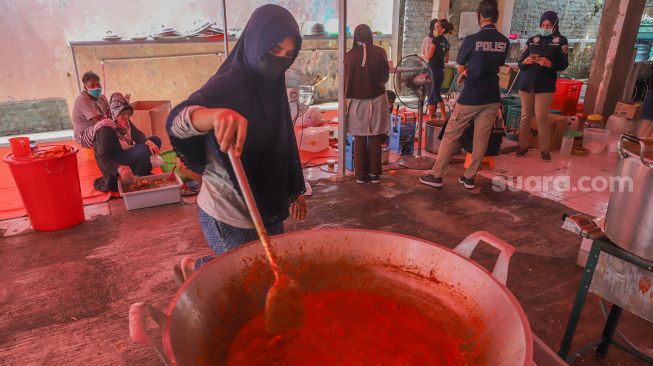 Warga memasak sambal di Dapur Umum Kasih Bayangkari Peduli Polda Metro Jaya, Tanah Abang, Jakarta Pusat, Sabtu (16/5). [Suara.com/Alfian Winanto]