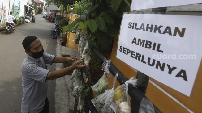 Warga mengambil paket sembako gratis di kawasan Jati Padang, Jakarta, Minggu (17/5). [Suara.com/Angga Budhiyanto]