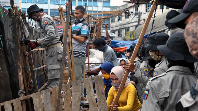 Anggota Satpol PP Kota Bogor bersama pedagang kaki lima (PKL) membongkar lapak di kawasan Pasar Anyar, Kota Bogor, Jawa Barat, Selasa (19/5). [ANTARA FOTO/Arif Firmansyah]