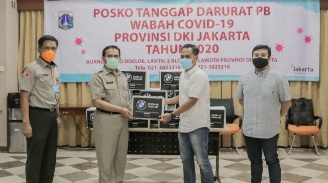 Plh Kepala Pelaksana BPBD DKI Jakarta, Sabdo Kurnianto, Sekretaris Daerah DKI Jakarta Saefullah, Pengurus BMW Car Clubs Indonesia (BMWCCI) Jakarta Chapter Heru K Wijaya dan Drifter Profesional sebagai perwakilan komunitas dan penggemar BMW Akbar Rais menyerahkan bantuan untuk masyarakat yang terdampak pandemi Covid-19 di Balai Kota DKI Jakarta, Selasa (19/5). (BPBD). [Suara.com/Oke Atmaja]