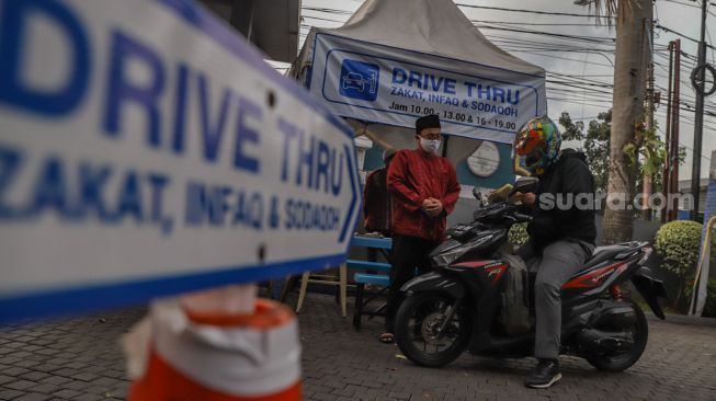 Pengendara motor membayar zakat fitrah secara Drive Thru di Masjid Nurul Hidayah, Tanah Kusir, Jakarta Selatan, Rabu (20/5).  [Suara.com/Alfian Winanto]