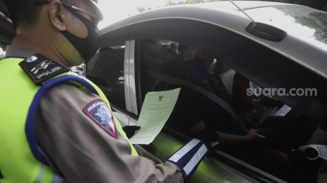 Petugas Kepolisian memeriksa kendaraan di Pos Penyekatan Jalur Mudik di Gerbang Tol Cikarang Barat, Kabupaten Bekasi, Jawa Barat, Rabu (20/5). [Suara.com/Angga Budhiyanto]