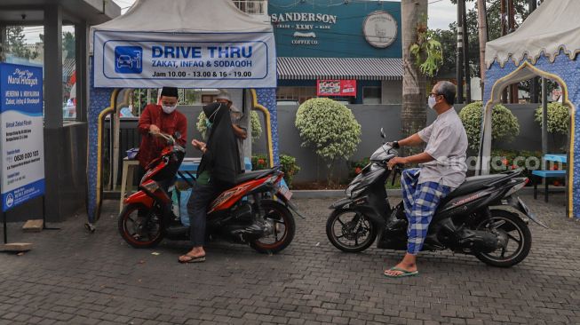 Pengendara motor mengantri membayar zakat fitrah di Masjid Nurul Hidayah, Tanah Kusir, Jakarta Selatan, Rabu (20/5). [Suara.com/Alfian Winanto]