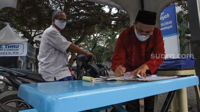 Petugas mencatat zakat fitrah yang dibayarkan di Masjid Nurul Hidayah, Tanah Kusir, Jakarta Selatan, Rabu (20/5). [Suara.com/Alfian Winanto]