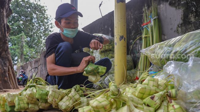 Pedagang mengikat satu beberapa kulit ketupat di Pasar Palmerah, Jakarta Pusat, Kamis (21/5). [Suara.com/Alfian Winanto]
