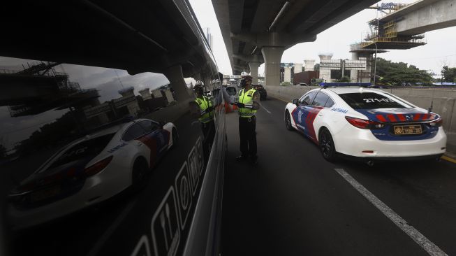 Petugas Kepolisian memeriksa kendaraan di Pos Penyekatan Jalur Mudik di Gerbang Tol Cikarang Barat, Kabupaten Bekasi, Jawa Barat, Rabu (20/5). [Suara.com/Angga Budhiyanto]