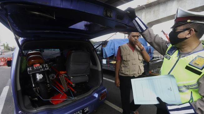 Petugas Kepolisian mengarahkan kendaraan untuk keluar dari Tol Jakarta-Cikampek, Cikarang Barat, Kabupaten Bekasi, Jawa Barat, Rabu (20/5). [Suara.com/Angga Budhiyanto]  