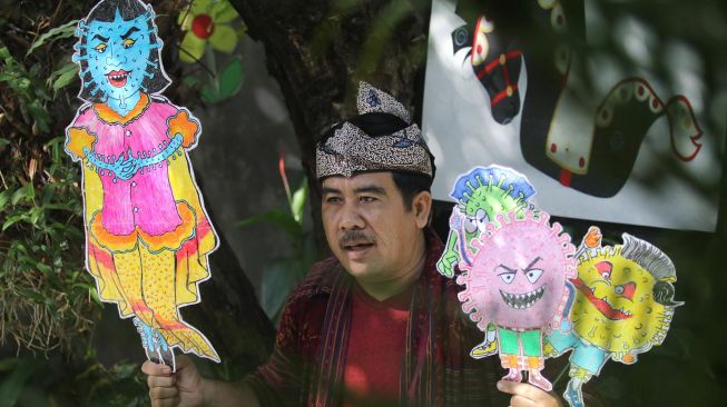 Kepala sekolah SD Katolik Frateran II Fx. Luhkita Heru Pratama memainkan wayang COVID-19 untuk disampaikan secara daring kepada murid-muridnya di Kota Kediri, Jawa Timur, Jumat (22/5).  [ANTARA FOTO/Prasetia Fauzani]
