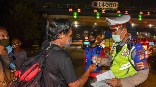 Petugas kepolisian memeriksa dokumen milik calon pemudik yang terjaring razia penyekatan di Pintu Tol Cikarang Barat, Bekasi, Jawa Barat, Kamis (21/5/2020). [ANTARA FOTO/Nova Wahyudi]