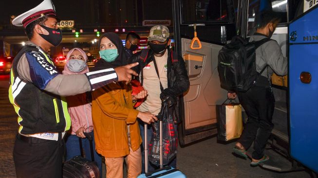 Petugas kepolisian mengarahkan calon pemudik yang terjaring razia penyekatan untuk menaiki bus yang akan membawa mereka ke Terminal Pulogebang, Jakarta, di Pintu Tol Cikarang Barat, Bekasi, Jawa Barat, Kamis (21/5/2020). [ANTARA FOTO/Nova Wahyudi]
