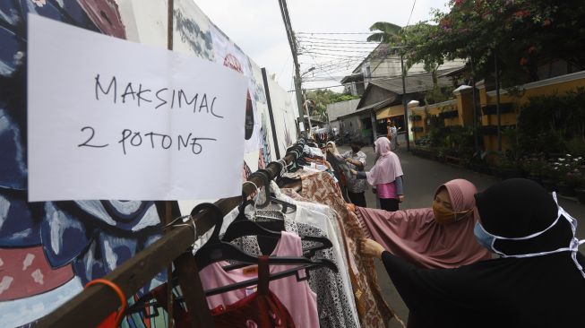 Warga memilih baju bekas layak pakai hasil sumbangan di RT 02 RW 04 Kelurahan Jati Padang, Jakarta, Jumat (22/5).  [Suara.com/Angga Budhiyanto]
