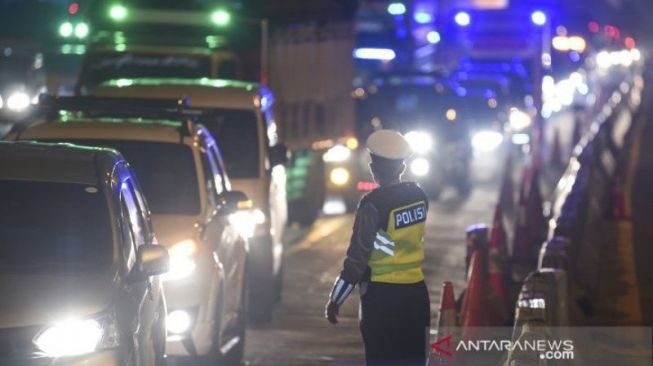 Petugas Kepolisian mengarahkan kendaraan pribadi yang melintas di tol Jakarta-Cikampek untuk ke luar melalui pintu tol Cikarang Barat 3, Jawa Barat. Pengalihan ini sebagai upaya penyekatan gelombang pemudik jelang perayaan Hari Raya Idul Fitri 1441 H dari arah Jakarta menuju Jawa Tengah [ANTARA FOTO/Nova Wahyudi/pras].