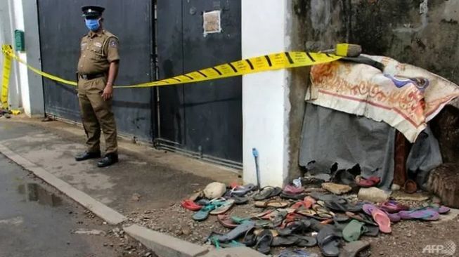 Seorang polisi berjaga-jaga di luar sebuah gudang tempat pembagian bantuan di Kolombo. (AFP/STR)