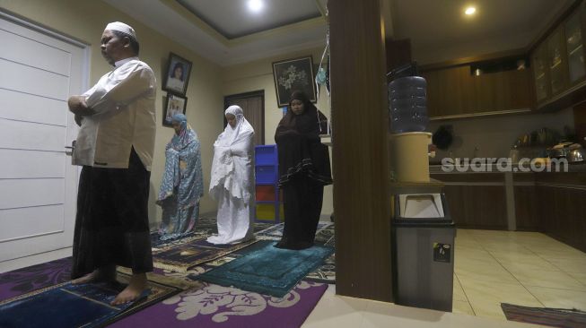 Ahmad Fauzi bersama keluarganya melaksanakan shalat tarawih di rumahnya di kawasan Jati Padang, Pasar Minggu, Jakarta Selatan, Rabu (29/4). [Suara.com/Angga Budhiyanto]