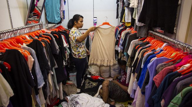 Pedagang pakaian bekas menawarkan dagangannya melalui sosial media di Pasar Senen Blok III, Jakarta Pusat, Jumat (22/5).  [ANTARA FOTO/Dhemas Reviyanto]