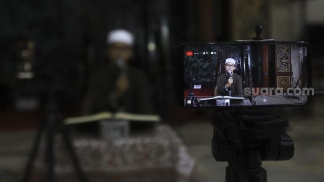 Imam Ustaz H Deden M Ramadhan menyiarkan acara tadarus Al-Quran secara dalam jaringan di Masjid Agung Sunda Kelapa, Jakarta, Selasa (28/4).  [Suara.com/Angga Budhiyanto]