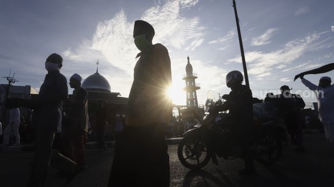 Umat Islam bergegas meninggalkan Masjid Jami An-Nur usai melaksanakan shalat Idul Fitri 1 Syawal 1441 Hijriah secara berjamaah di dalam mobilnya di ruas Jalan Jenderal Sudirman, Kranji, Bekasi, Jawa Barat, Minggu (24/5). [Suara.com/Angga Budhiyanto]  