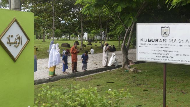 Warga berdoa di kuburan masal Tsunami Desa Ulee Lheue, Banda Aceh, Aceh, Minggu (24/5). [ANTARA FOTO/Ampelsa]