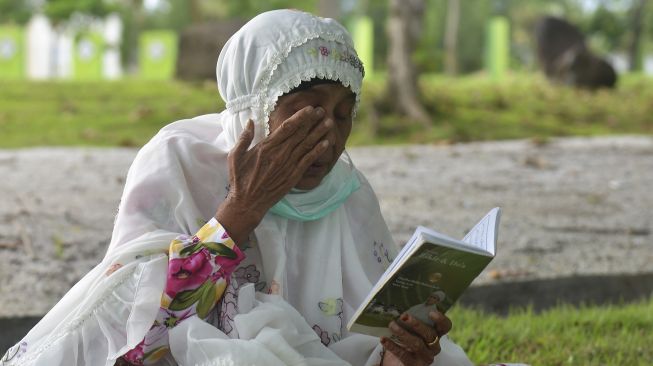 Warga berdoa di kuburan masal Tsunami Desa Ulee Lheue, Banda Aceh, Aceh, Minggu (24/5). [ANTARA FOTO/Ampelsa]