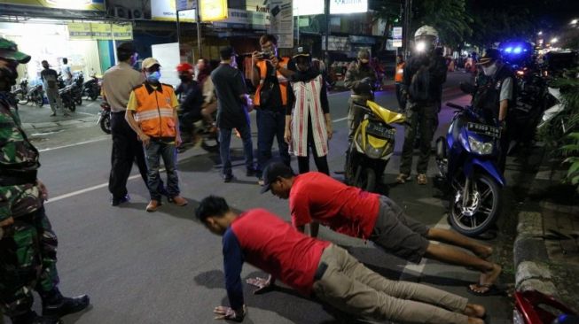  Pelanggar PSBB dikenakan sanksi berupa push-up usai terjaring patroli gabungan Kelurahan Malaka Sari, dan Kelurahan Malaka Jaya beserta TNI-Polri di sejumlah titik keramaian di Kecamatan Duren Sawit, Jakarta Timur, Sabtu malam [ANTARA/Fianda Rassat].