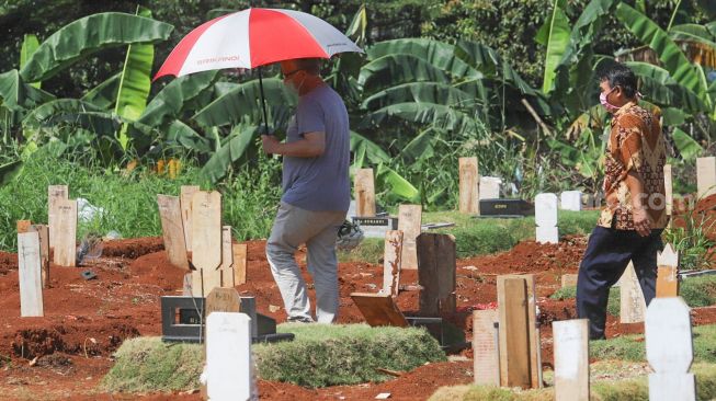 Keluarga berkunjung ke makam khusus korban Covid-19 di TPU  Pondok Ranggon, Jakarta Timur, Senin (25/5). [Suara.com/Alfian Winanto]