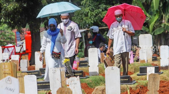 Keluarga berziarah ke makam khusus korban Covid-19 di TPU  Pondok Ranggon, Jakarta Timur, Senin (25/5).  [Suara.com/Alfian Winanto]