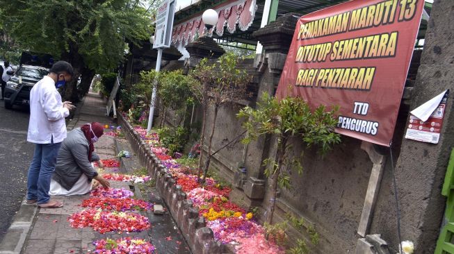 Warga melakukan ziarah kubur saat Hari Raya Idul Fitri di luar pagar kawasan Pemakaman Muslim Wanasari, Denpasar, Bali, Minggu (24/5).  [ANTARA FOTO/Fikri Yusuf]