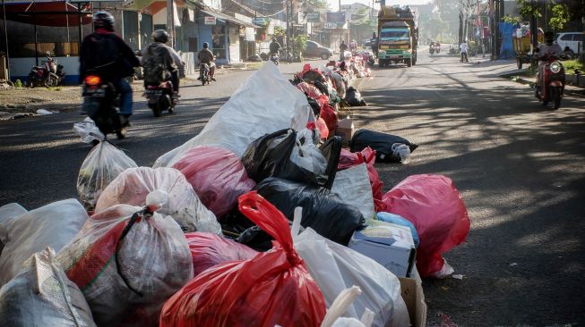 Sampah yang menumpuk di pembatas jalan di Ciledug, Tangerang, Banten, Senin (25/5). [ANTARA FOTO/Rivan Awal Lingga]