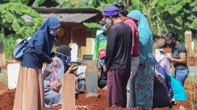 Keluarga berdoa di makam khusus korban Covid-19 di TPU  Pondok Ranggon, Jakarta Timur, Senin (25/5). [Suara.com/Alfian Winanto]