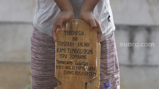 Petugas menancapkan nisan bertuliskan Indonesia bin Terserah di TPU Jombang, Tangerang Selatan, Selasa (26/5). [Suara.com/Angga Budhiyanto]