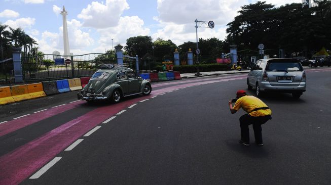 Seorang warga mengambil foto kendaraannya dengan latar belakang Monas di Jakarta, Senin (25/5). [ANTARA FOTO/Akbar Nugroho Gumay]
