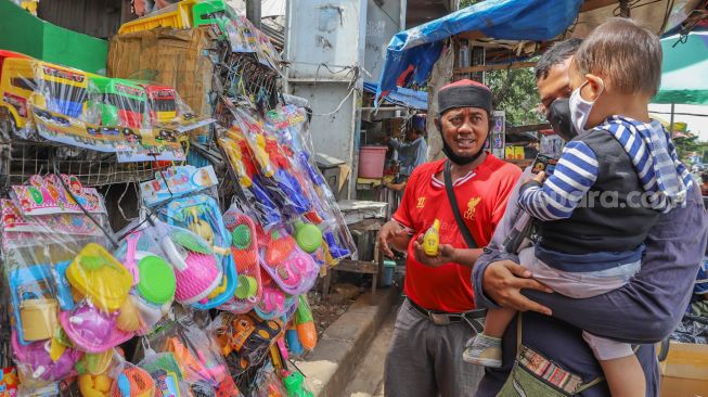 Orang tua menemani anaknya memilih mainan yang akan dibeli di Pasar Gembrong, Jakarta Timur, Selasa (26/5). [Suara.com/Alfian Winanto]
