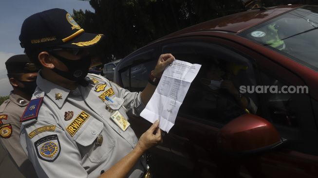 Petugas gabungan mengecek Surat Ijin Keluar-Masuk (SIKM) Jakarta kepada pengendara di pos pemantauan PSBB Pasar Jumat, Jakarta Selatan, Selasa (26/5).  [Suara.com/Angga Budhiyanto]