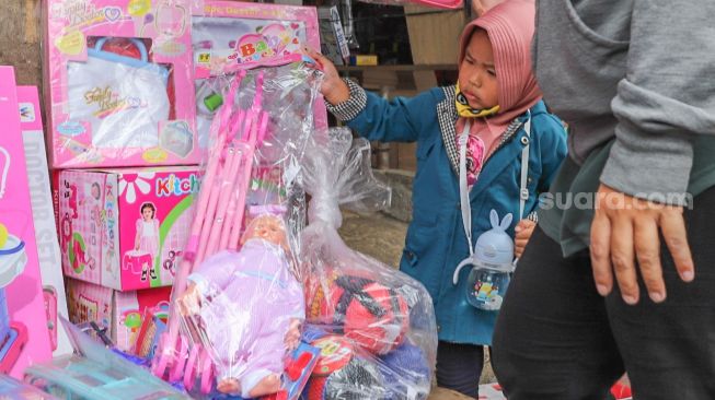 Seorang anak memilih mainan di Pasar Gembrong, Jakarta Timur, Selasa (26/5). [Suara.com/Alfian Winanto]
