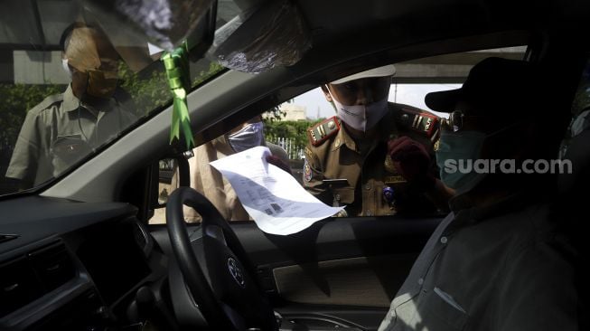 Petugas gabungan melakukan pengecekan Surat Ijin Keluar-Masuk (SIKM) Jakarta kepada pengendara di pos pemantauan PSBB Pasar Jumat, Jakarta Selatan, Selasa (26/5).  [Suara.com/Angga Budhiyanto]