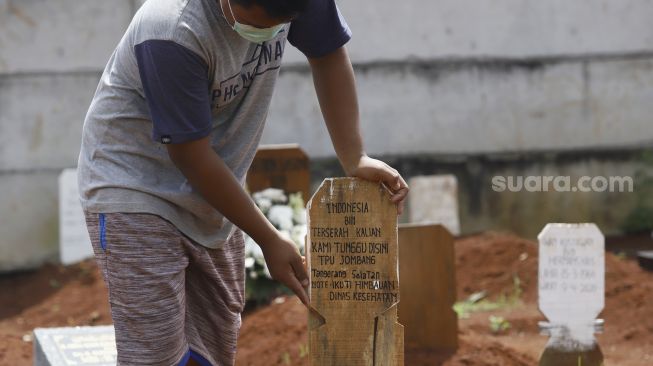 Petugas menancapkan nisan bertuliskan Indonesia bin Terserah di TPU Jombang, Tangerang Selatan, Selasa (26/5). [Suara.com/Angga Budhiyanto]