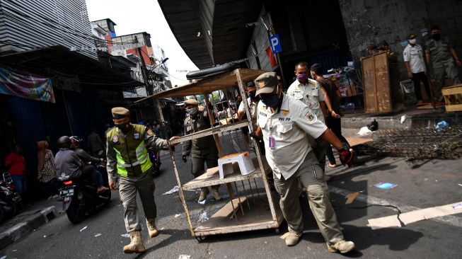 Anggota Satpol PP membawa etalase saat penertiban lapak pedagang di kolong jembatan layang Pasar Pagi Asemka, Jakarta Barat, Rabu (27/5/2020). [ANTARA FOTO/Sigid Kurniawan]
