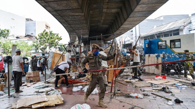 Anggota Satpol PP membersihkan lapak pedagang yang berjualan di kolong jembatan layang Pasar Pagi Asemka, Jakarta Barat, Rabu (27/5).  [ANTARA FOTO/Sigid Kurniawan]