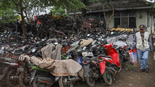 Petugas melintas diantara bangkai sepeda motor di tempat penampungan Teluk Pucung, Bekasi, Jawa Barat, Rabu (27/5). [Suara.com/Alfian Winanto]