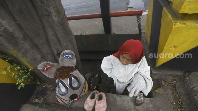 Selvi (20) mengenakan kostum badut kelinci bersiap mengamen di jembatan di kawasan Cibubur, Jakarta, Kamis (28/5). [Suara.com/Angga Budhiyanto]