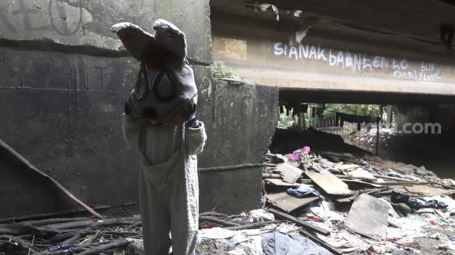 Selvi (20) mengenakan kostum badut kelinci bersiap mengamen di jembatan di kawasan Cibubur, Jakarta, Kamis (28/5). [Suara.com/Angga Budhiyanto]