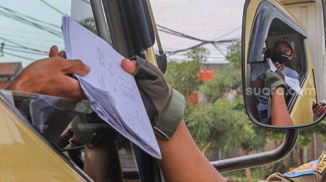 Pengendara truk berpelat daerah menunjukan surat-surat kepada petugas saat melintas di Jalan Brigif, Jakarta Selatan, Kamis (28/5). [Suara.com/Alfian Winanto]