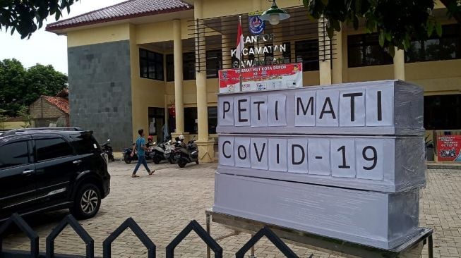 Tiga peti mati bertuliskan 'Peti Mati Covid-19 ditempatkan di depan Kantor Kecamatan Sawangan, Kota Depok. [Suara.com/Supriyadi]