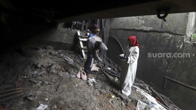 Selvi (20) didampingi suaminya Dede (20) mengenakan kostum badut kelinci di bawah jembatan di kawasan Cibubur, Jakarta, Kamis (28/5). [Suara.com/Angga Budhiyanto]