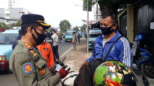 Petugas saat memeriksa SIKM dan KTP pengendara di check point PSBB Pasar Rebo, Jaktim. (Suara.com/Bagaskara).