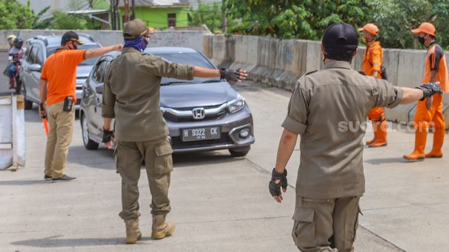 Petugas memberhentikan kendaraan berpelat daerah di Jalan Brigif, Jakarta Selatan, Kamis (28/5). [Suara.com/Alfian Winanto]