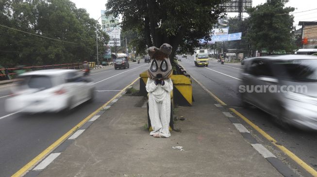 Selvi (20) mengenakan kostum badut kelinci mengamen di jembatan di kawasan Cibubur, Jakarta, Kamis (28/5). [Suara.com/Angga Budhiyanto]