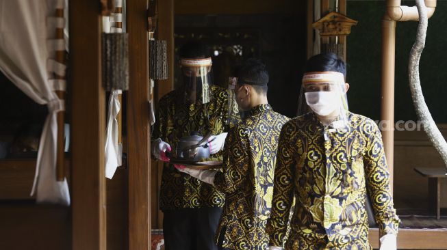 Pelayan menggunakan alat pelindung wajah, masker dan sarung tangan saat melayani pelanggan di salah satu rumah makan di kawasan Pajajaran, Kota Bogor, Jawa Barat, Jumat (29/5). [Suara.com/Angga Budhiyanto]