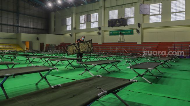 Petugas merapikan tempat tidur di ruang karantina pemudik di Gelanggang Remaja Pulogadung, Jakarta Timur, Jumat (29/5). [Suara.com/Alfian Winanto]